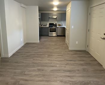 A view of a kitchen and a hallway with wood flooring